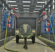 Blast room with in-floor belt abrasive recovery, supplementary vacuum recovery, and articulating work platforms