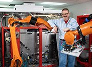 Dr. Jeff Dulaney, President and CEO of LSP Technologies, leans on some friendly robots under configuration for a Procudo® Laser Peening System being assembled at the company’s Dublin, Ohio, build room.