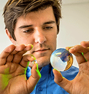 Laser Optical Designer Tim Gorman shows how much smaller the micro-lenses and mirrors must be to deliver laser peening to hard-to-reach parts.